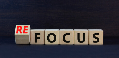 Focus or refocus symbol. Turned wooden cubes and changed the concept word focus to refocus. Beautiful black table black background. Business focus or refocus concept. Copy space.