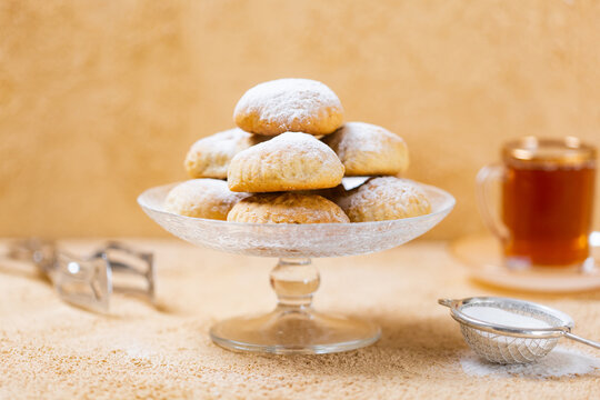 traditional Islamic Feast,Cookies for celebration of Eid El Fitr (Kahk) dusted with fine sugar with a cub of tea in the background 