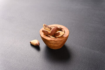 Brazil nut in woodenbowl on dark background.