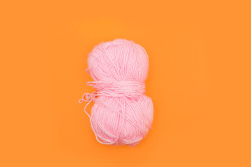 A skein of pink threads on an orange background