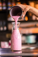 Sirviendo batido de fresa en vaso de vidrio 