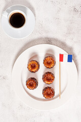 A cup of coffee and French dessert canele on grey background