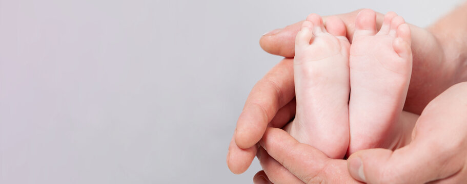 Parent Holding In The Hands Feet Of Newborn Baby On White Background