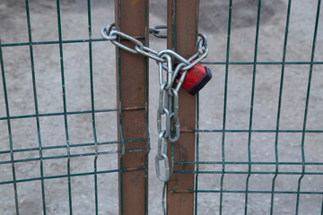 A lock with a chain hangs on the doors.Closed fence doors.