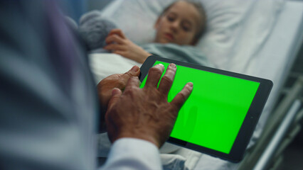 Doctor touching tablet green screen closeup. Sick girl lying in hospital bed.
