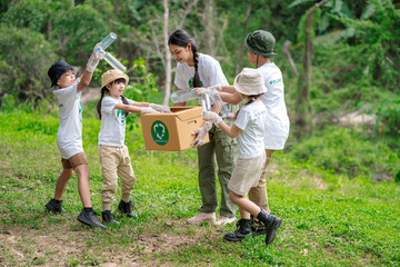 Volunteer Asian and children are collecting plastic bottles into garbage box to reduce global warming and environmental pollution. Volunteering and recycling concept.