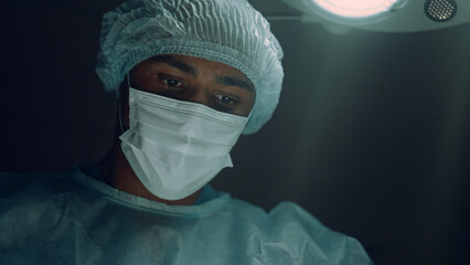 Focused surgeon performing surgical operation in intensive care unit portrait.