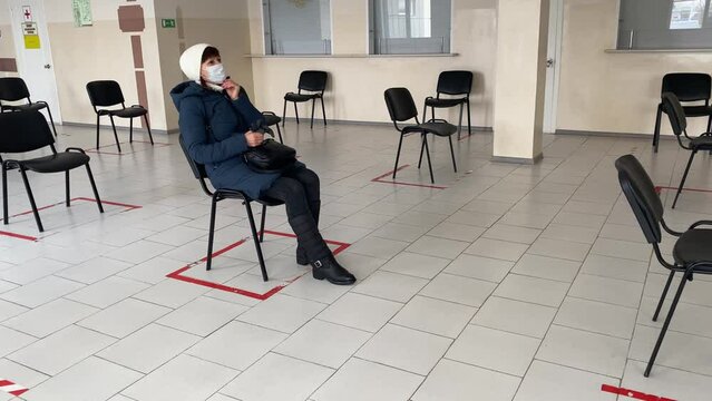 Concept of social distancing in the waiting room at the train station with one masked person sitting on a chair, keeping a distance. A new normal life to prevent covid-19 infection during a pandemic.