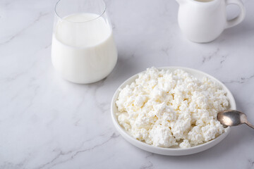 Bowl with fresh cottage cheese and milk on table. Space for text