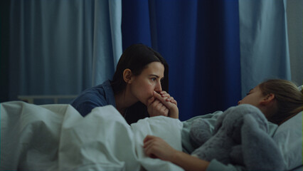 Fototapeta premium Mother sitting sick daughter after surgical treatment in modern hospital ward. 