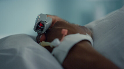 Patient finger pulse monitoring device closeup. Medical catheter on male hand.