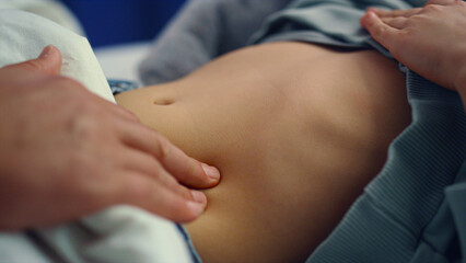 Obraz na płótnie Canvas Doctor hands checking stomach of little sick girl in hospital ward closeup. 