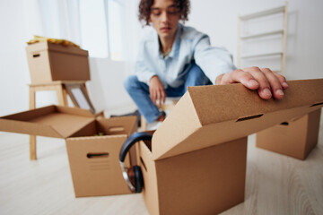 guy with curly hair sitting on a chair with boxes moving interior