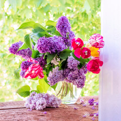 Lilacs and tulips in a vase on the window.Beautiful and delicate flowers.