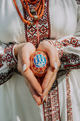 Ukrainian woman holding in hands Easter eggs with national symbol of Ukraine - trident decoration. Lady in embroidery vyshyvanka dress.