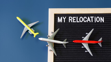 Toy passenger planes next to a felt board with the inscription my relocation. The concept of moving, migration and relocation. Blue background.
