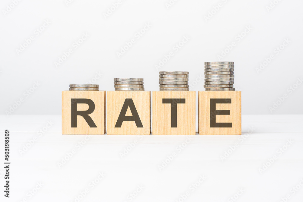 Fototapete rate text written on wooden block with stacked coins on white background