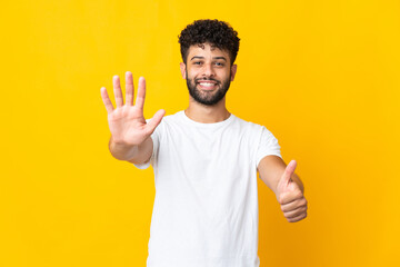 Fototapeta premium Young Moroccan man isolated on yellow background counting six with fingers