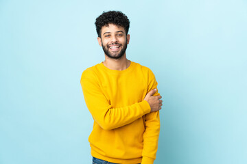 Young Moroccan man isolated on blue background laughing