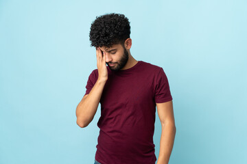 Young Moroccan man isolated on blue background with headache