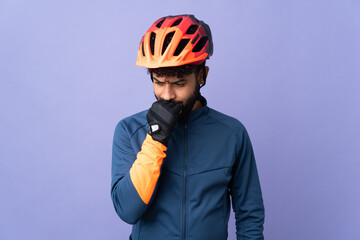 Young Moroccan cyclist man isolated on purple background having doubts - obrazy, fototapety, plakaty