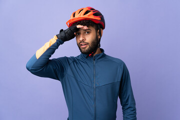Young Moroccan cyclist man isolated on purple background doing surprise gesture while looking to the side - obrazy, fototapety, plakaty