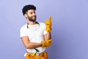 Young electrician Moroccan man isolated on purple background pointing up a great idea