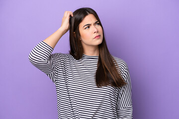 Young Brazilian woman isolated on purple background having doubts while scratching head - obrazy, fototapety, plakaty
