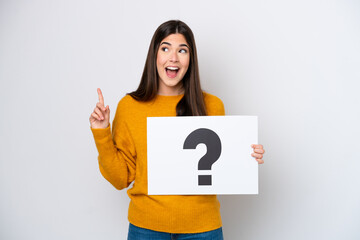 Young Brazilian woman isolated on white background holding a placard with question mark symbol and...