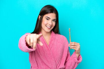 Young Brazilian woman brushing teeth isolated on blue background points finger at you with a confident expression