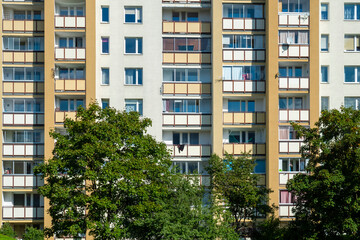 Residential building with many balconies and trees in front of it on a sunny summer day