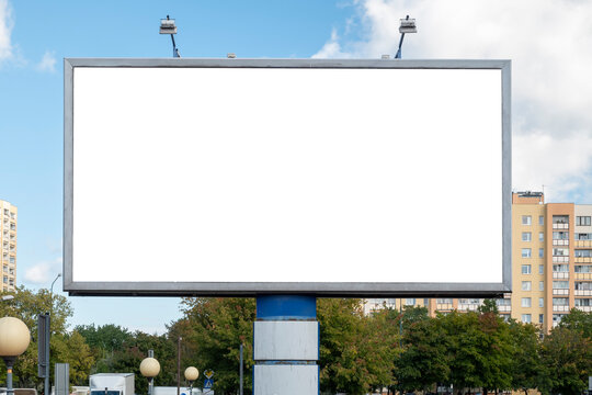 Blank white advertising billboard near residential buildings in the city on a sunny summer day.