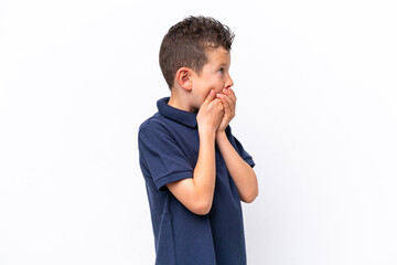 Little caucasian boy isolated on white background covering mouth and looking to the side