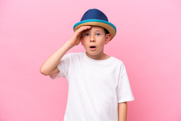 Little caucasian boy wearing a hat isolated on pink background with surprise and shocked facial expression