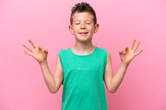 Little caucasian boy isolated on pink background in zen pose