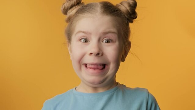 Happy girl with toothless smile looking at camera at yellow background. Loss of deciduous tooth. Cheerful child expressing positive emotions. 4K, UHD