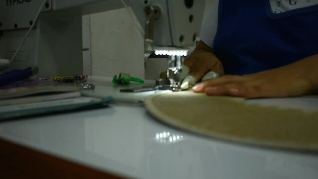 Moving sewing machine needle. The close-up of the sewing machine needle moves rapidly up and down. The seamstress sews hats in the sewing workshop sewing hat brim. Sewing strap in hat factory