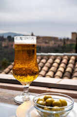 Spanish beer and glass bowl with green andalusian olives served on outdoor terrace with view on Sierra Nevada mountains in Granada, Andalusia, Spain