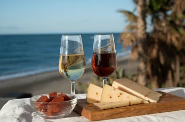 Fotobehang Spanish hard Andalusian cheese filled with sweet sherry served outdoor with membrillo jam with two glasses of sherry wine with beach and blue sea on background © barmalini