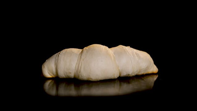 Zoom in shot: croissants baking and rising on tray against black background - timelapse, close up view, black background. French cuisine, breakfast, food, cooking, pastry and time lapse concept