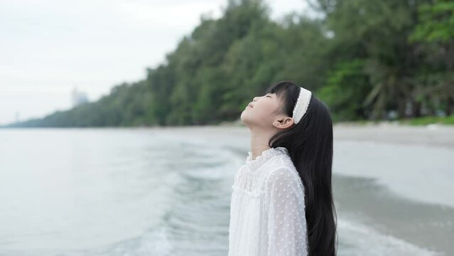 Holiday concept of 4k Resolution. Asian girl looking at the view on the beach. She was feeling refreshed with good weather.
