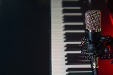Synthesizer, midi keyboard and microphone on a black background. Close-up. Recording studio, concerts, performances, rehearsals, workplace of a musician, singer, composer.