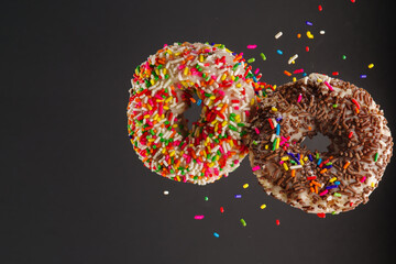 Two colored sweet donuts on a gray background. Levitation. Confectionery, cafe, restaurant, recipe book, culinary blog. Sweet food, holiday, birthday, youth culture.