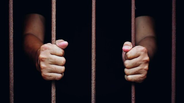 hand man hold steel in jail on black background.concept for prisoner,sadness,detain,erroneousness