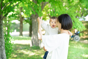 Obraz premium 新緑の葉っぱを触る母親と1歳の女の子