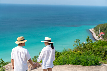 Happy Asian family couple holding hands and walking together while travel on tropical island...