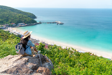 Young beautiful Asian woman with backpack solo travel on tropical island mountain peak in summer...