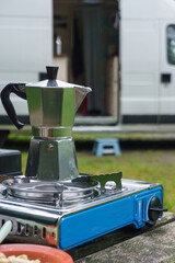 Aluminium Espresso maker on a gas stove for camping ready to start the day with mobile home in the background