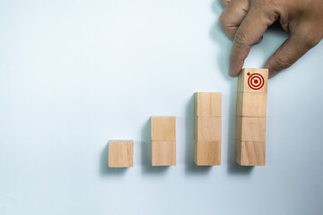 Top view hand place wooden blocks set to step with icon arrow to target. Concept for growth business and targeting.