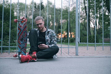 Young man using a cellphone while sitting at the skatepark.